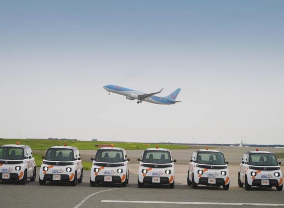 Un avion survole des voitures électriques utilisées par l'aéroport